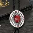 Western Cowboy Bolo Tie Necklace with red stone and geometric pattern on a textured black background