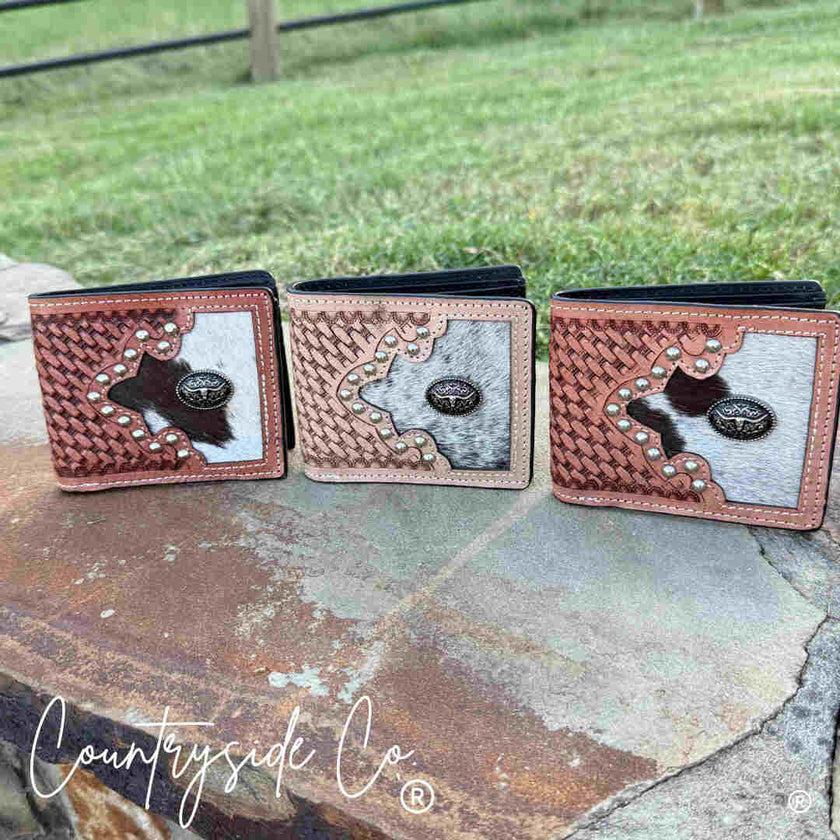 Three Buckhorn Cowhide Men's Wallets on a stone surface outdoors.