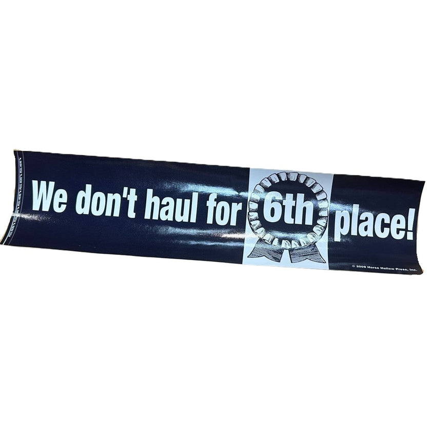 A black bumper sticker with white text that reads 'We don't haul for 6th place!' and a graphic of a white number 6 in a circle.