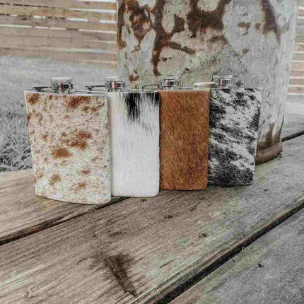 Four Cowhide Flasks, Stainless Steel on a wooden surface.
