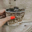 Person holding a cowhide-patterned Cowhide Flask Stainless Steel on a wooden surface