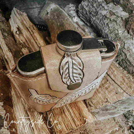 Desperado Tooled  Leather Flask with feather design on a wooden surface, featuring 'Countryside Co' branding.