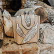 Desperado Tooled  Leather Flask with leather cover featuring feather designs on a wooden background
