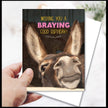 Birthday card with a donkey's face and humorous text, held by a hand.