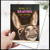 Birthday card with a donkey's face and humorous text, held by a hand.