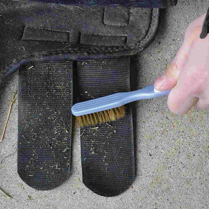 Person cleaning a horse boot with Cashel Hook and Loop Brush