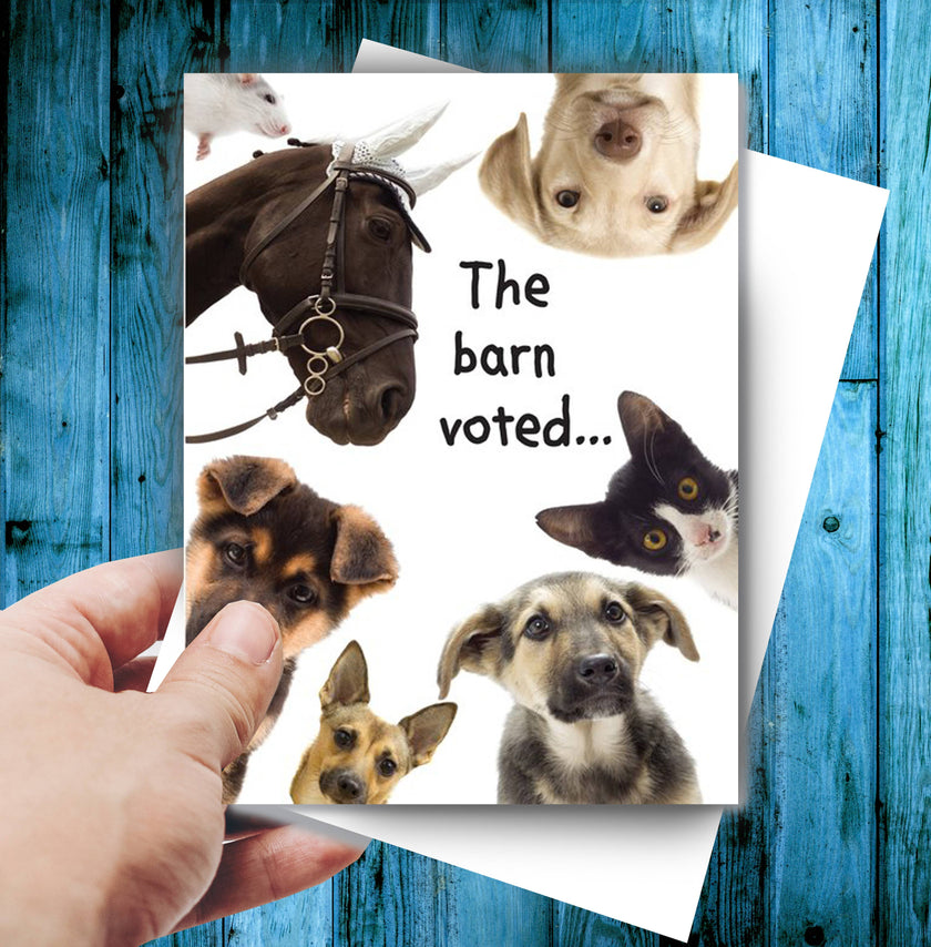 Horse Birthday Card: The Barn Voted with animals and text 'The barn voted...' held by a hand on a blue wooden background