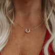 Close-up of a person wearing a gold necklace with a horseshoe pendant.