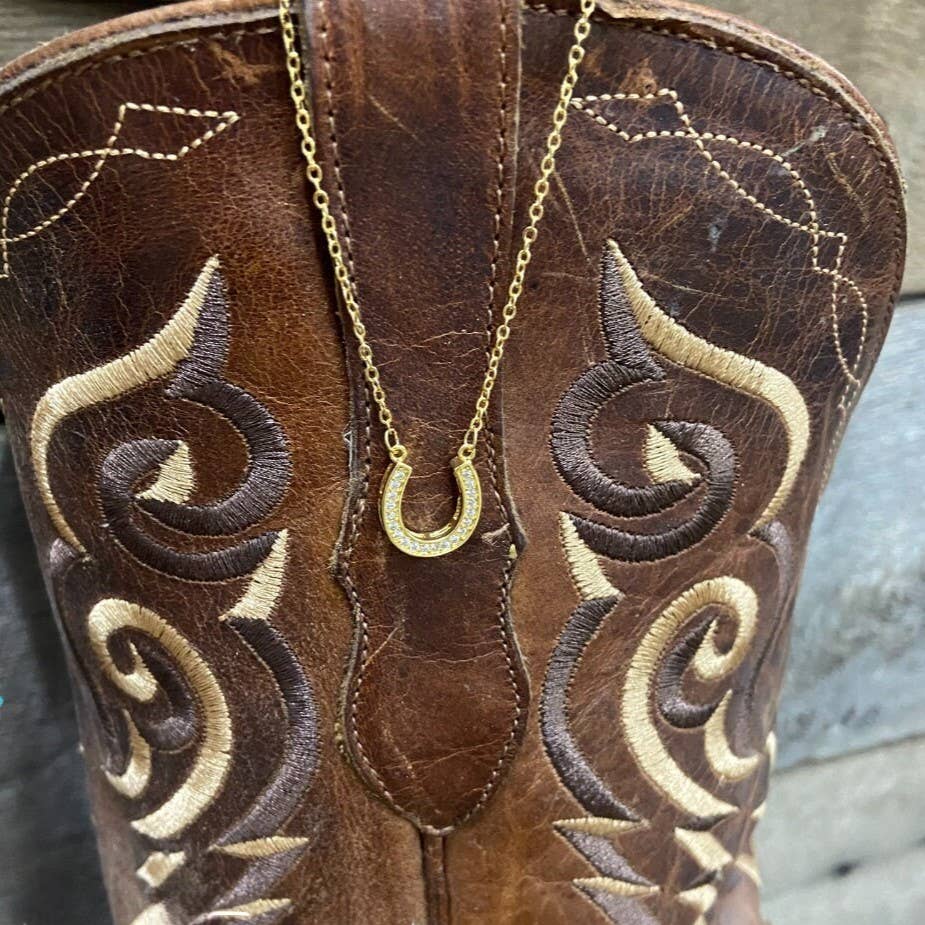 a gold necklace on a Brown embroidered boot.