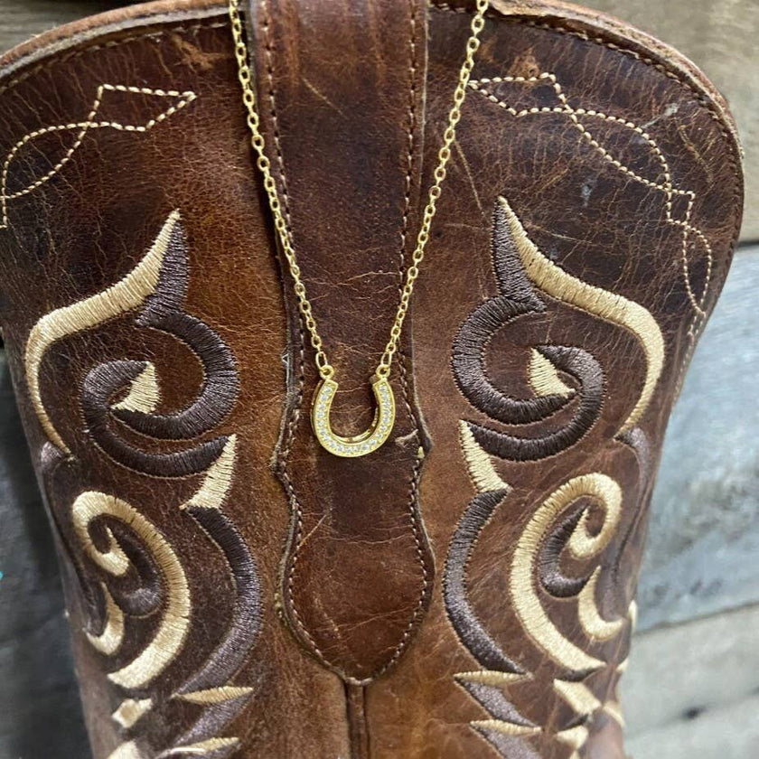 a gold necklace on a Brown embroidered boot.