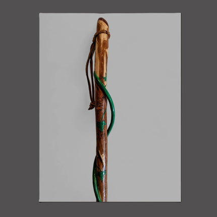 Wooden walking stick with green accents on a gray background