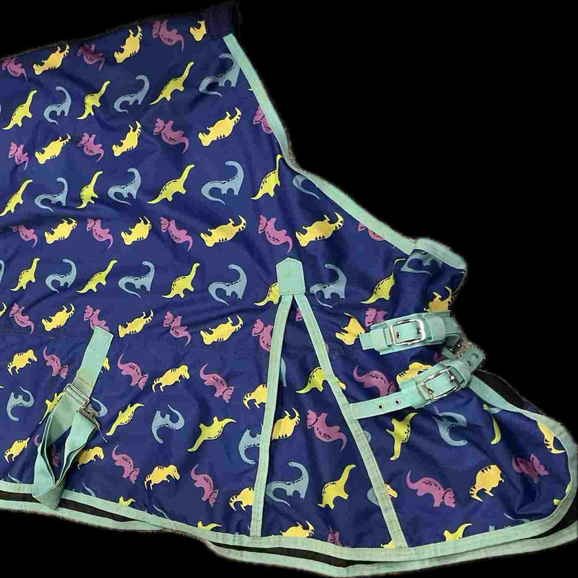 Navy blue horse blanket with colorful dinosaur pattern, and green trim and closures