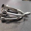 A pair of silver spurs with black nylon straps.