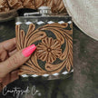Hand holding a Leather Flask Stainless Steel with intricate brown designs on a dark surface, featuring 'Countryside Co' branding.