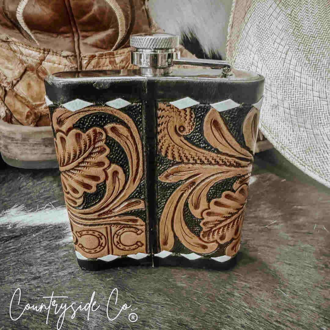 Handcrafted Leather Flask Stainless Steel with intricate patterns on a rustic surface, featuring the 'Countryside Co' brand.