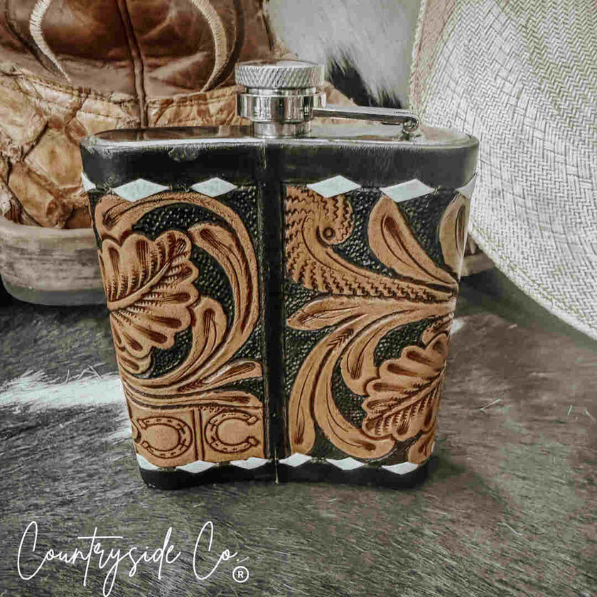 Handcrafted Leather Flask Stainless Steel with intricate patterns on a rustic surface, featuring the 'Countryside Co' brand.