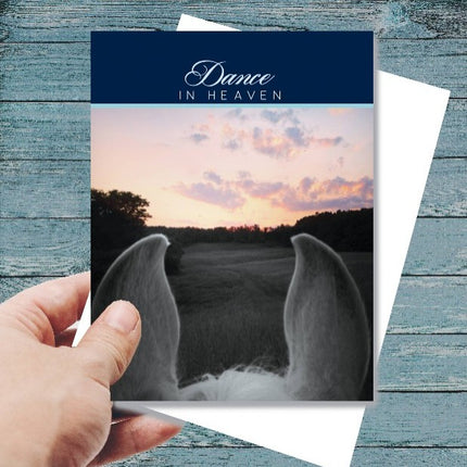 Sympathy Card - Dance in Heaven...with angel wings and sunset design held by a hand on a wooden surface