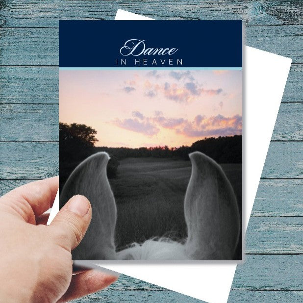 Sympathy Card - Dance in Heaven...with angel wings and sunset design held by a hand on a wooden surface