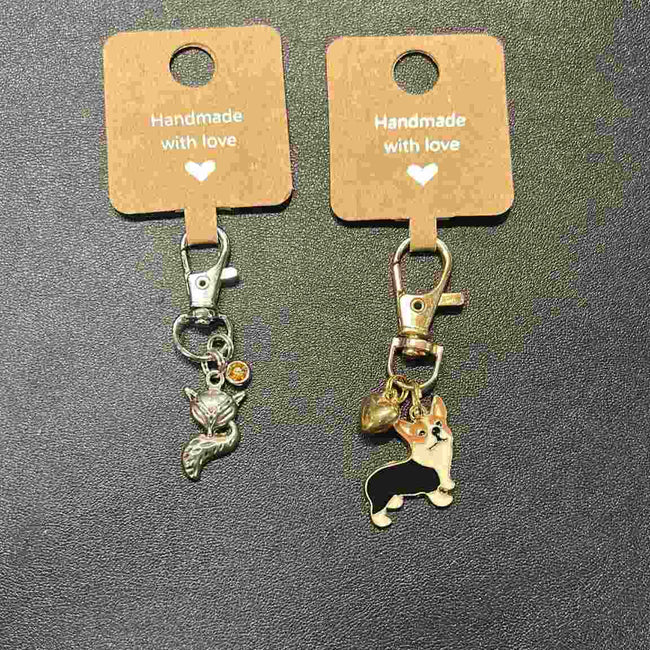 Two keychains with charms on brown cards labeled 'Handmade with love' -Handmade Animal Charm Key Chain.