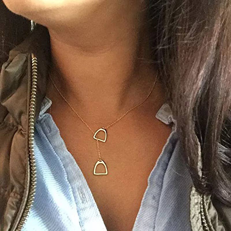 A person wearing a sterling silver necklace with two pendant stirrup iron accents.
